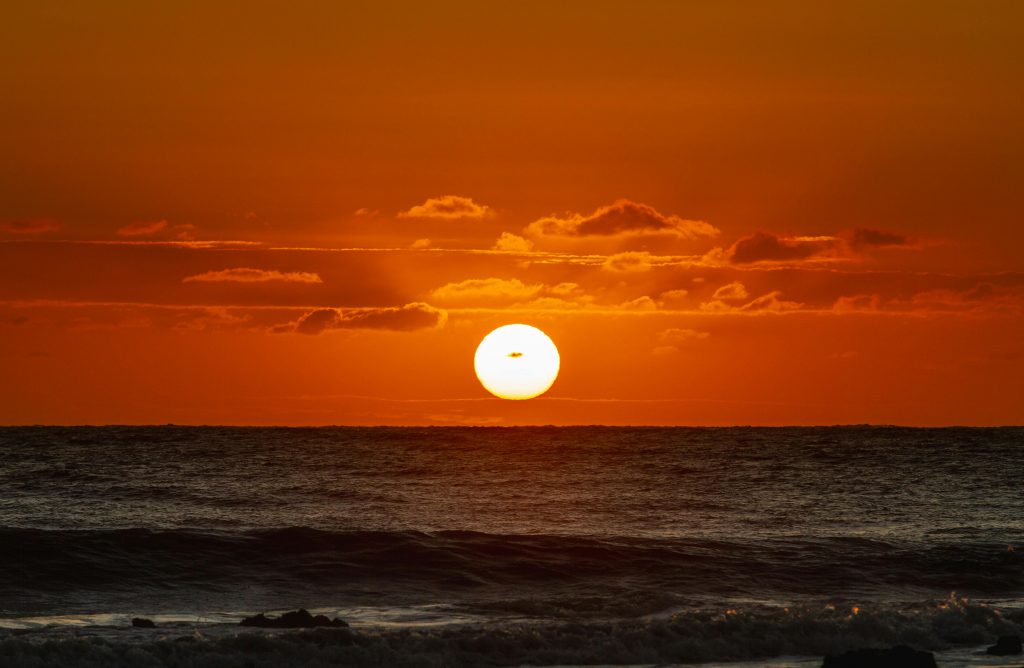 Dramatic sunset over the ocean waters at Baía Formosa, Brazil, showcasing vibrant orange hues.